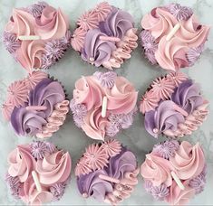 cupcakes with pink, purple and white frosting on a marble counter top