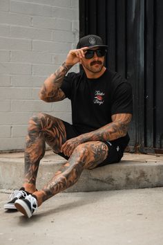 a man with tattoos sitting on the ground