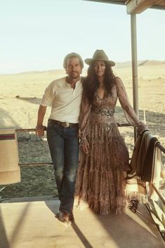 a man and woman standing next to each other in front of a fenced off area