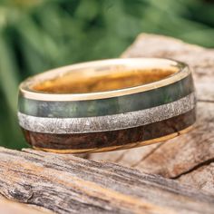 a wedding band with two different colored wood inlays sits on top of a piece of wood