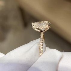 a close up of a person's hand holding an engagement ring