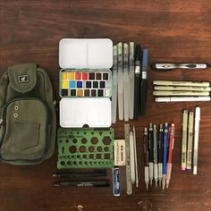 an assortment of art supplies including markers, pens and pencils on a wooden table