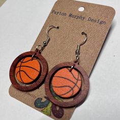 the hoop earrings are made out of wood and have an orange basketball painted on it