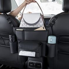 the back seat of a car with various items in it and someone holding a cell phone