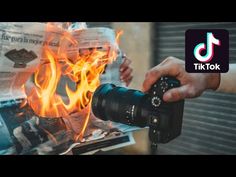 a person holding a camera in front of a fire