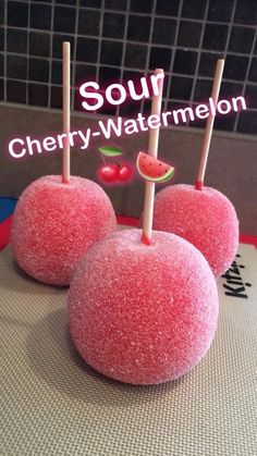 three watermelon pops sitting on top of a counter next to a sign that says sour cherry watermelon