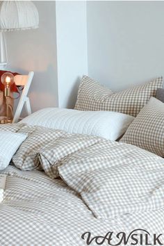 an unmade bed with brown and white checkered comforter, pillows and lamps