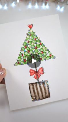 someone holding up a card with a christmas tree on it