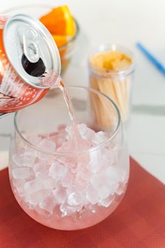 a glass filled with ice sitting on top of a table next to an orange slice