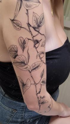 a woman's arm with flowers and leaves on it