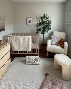 a baby's room with a crib, chair and ottoman