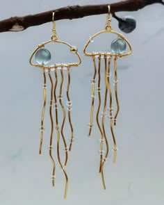 gold plated earrings with blue beads hanging from a branch