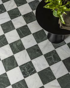 a black and white checkered tile floor with a potted plant on the end table