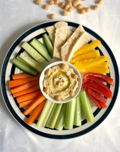 a plate with vegetables and hummus on it, including carrots, celery