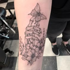 a woman's leg with flowers and a butterfly tattoo on the side of her arm