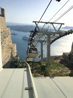 a cable car going up to the top of a hill with water in the background