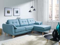 a living room with a blue sectional couch and white rugs on the floor in front of a window