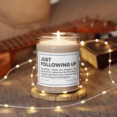 a lit candle sitting on top of a wooden table next to a string of lights