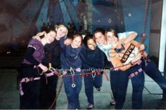 a group of people standing next to each other on a rope bridge with ropes around them