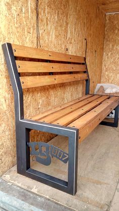 a wooden bench sitting inside of a building next to a cement slab and plywood wall