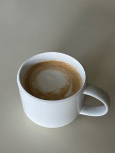 a white cup filled with liquid on top of a table