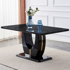 a black marble top dining table with gold trimmings on the legs and base