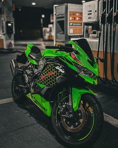 a green motorcycle parked in front of a gas station