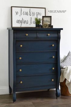 a blue dresser with gold knobs in a white room next to a framed sign that says, so i can kiss you anytime