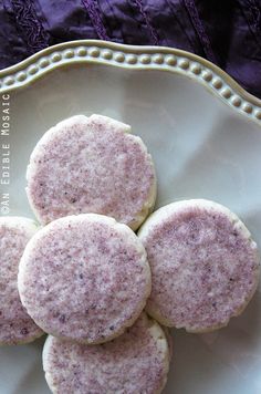 four cookies sitting on top of a white plate next to a purple lace table cloth