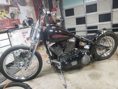 a black motorcycle parked in a garage next to a wall filled with shelves and tools