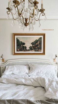 a bedroom with a chandelier hanging above the bed and paintings on the wall