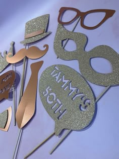 some gold and silver cake toppers are on a white table with the words happy 50th