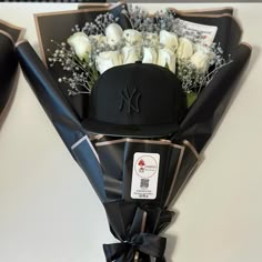 a bouquet of white roses in a black hat and ribbon tied around the back of it