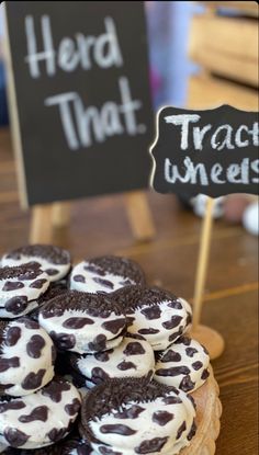 chocolate cookies with white frosting and black dots are on a wooden plate next to a sign that says herd that track wheels