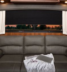 the couch is covered with a blanket and some glasses in front of a large window