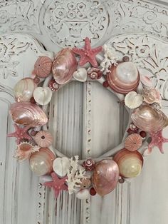 a wreath made out of seashells and starfish on a white door frame