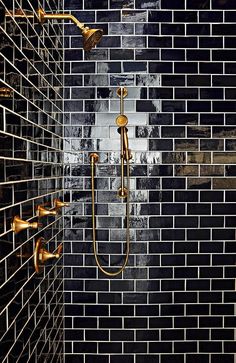 a tiled shower with gold faucet and hand held shower head