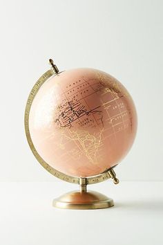 an antique pink globe on a gold stand, with the world map drawn on it