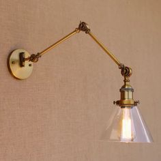 an old fashioned wall light with a clear glass shade on the arm and gold metal fittings