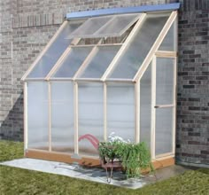 a small greenhouse in front of a brick building