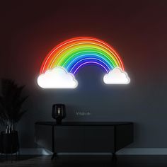 there is a neon sign with a rainbow in the sky above it and a black table