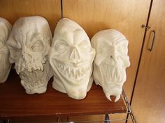 three white masks are sitting on a shelf