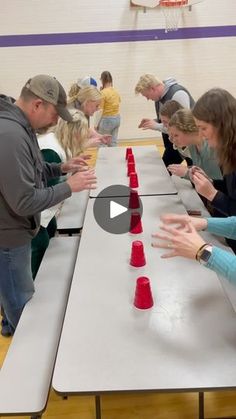 a group of people standing around a table with red cones on it and one person holding out their hands