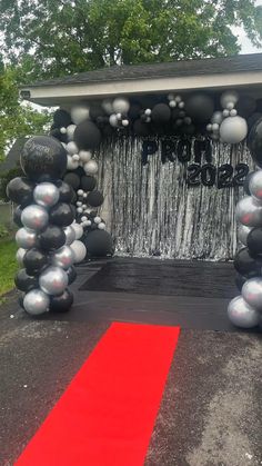 an entrance to a party with balloons and streamers on the red carpet in front of it