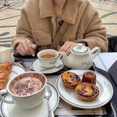 a woman is sitting at a table with coffee and pastries