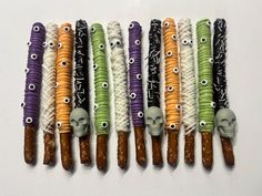 six halloween candy sticks with skulls and bones on them, all decorated in different colors