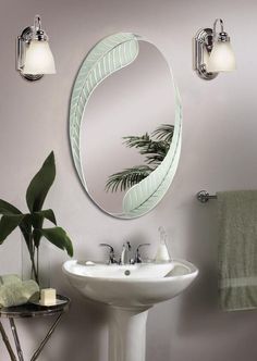 a white sink sitting under a mirror next to a green leafy wall mounted light