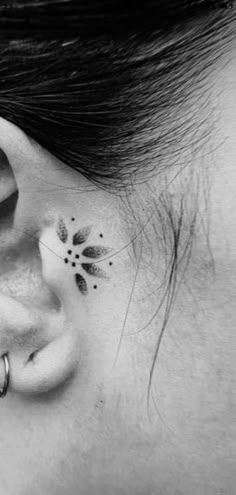 black and white photograph of a woman's ear with flower tattoos on her left side