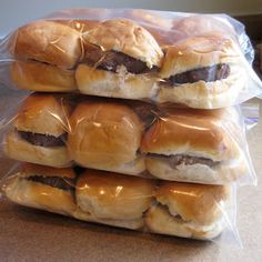 a stack of sandwiches wrapped in plastic sitting on top of a counter