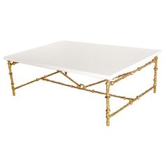 a white coffee table with gold legs and a square tray on the top that is shaped like bamboo sticks